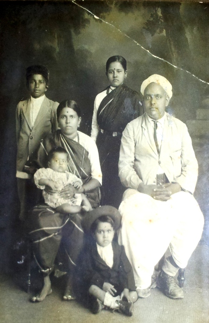 Photo taken in 2012 by T.S. Nagarajan of a 1924 framed photo hanging in his home. At the back: left, Uncle Ponnu\; right, Mr. Nagarajan’s mother, a year after her wedding. Sitting: left, Mr. Nagarajan’s maternal grandmother, with T.S. Satyan, Mr. Nagarajan’s older brother, in her lap\; right, Krishnaswamy Iyer, Mr. Nagarajan’s maternal grandfather. Sitting on the floor: A neighbour’s boy. He was included in the family photo because, in those days, it was common to consider your  neighbour’s children like your own children. © T.S. Nagarajan 2012.